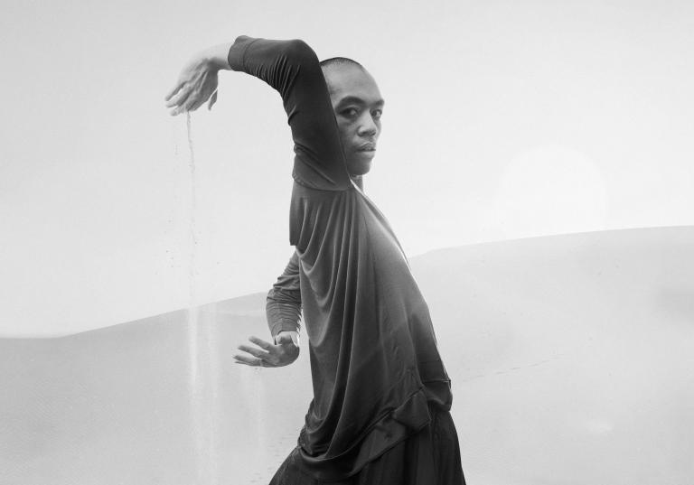 Michael Marquez, dansare på Skånes Dansteater står i ett ökenlandskap och strilar sand mellan sina händer.
