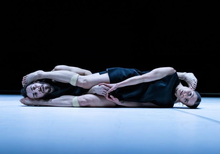 Dansarna Simone Frederick Scacchetti och Amy Josh ligger på golvet på sidan med sina fötter om varandras huvuden.