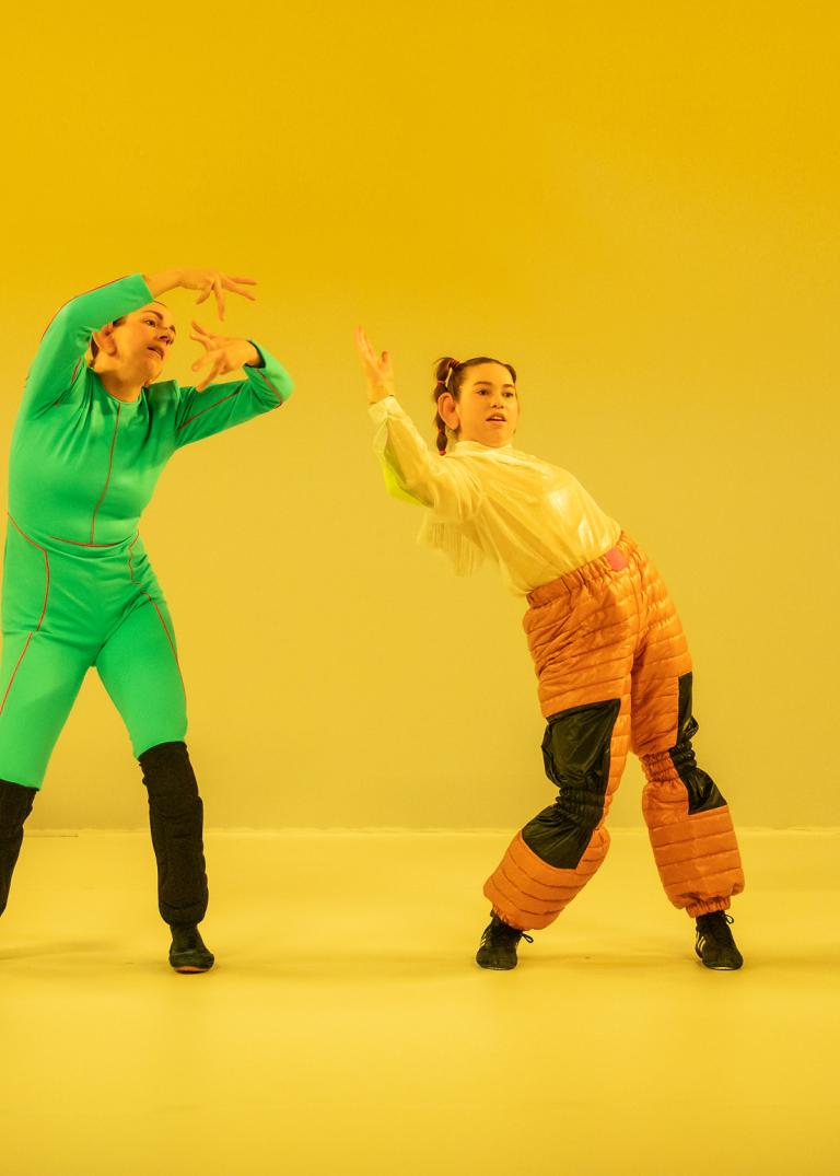 Fyra dansare står böjda åt olika håll i ett gulfärgat rum. 
