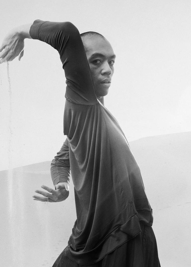 Michael Marquez, dansare på Skånes Dansteater står i ett ökenlandskap och strilar sand mellan sina händer.