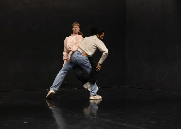 Två dansare står mot varandra med ben och armar vridna om den andre.