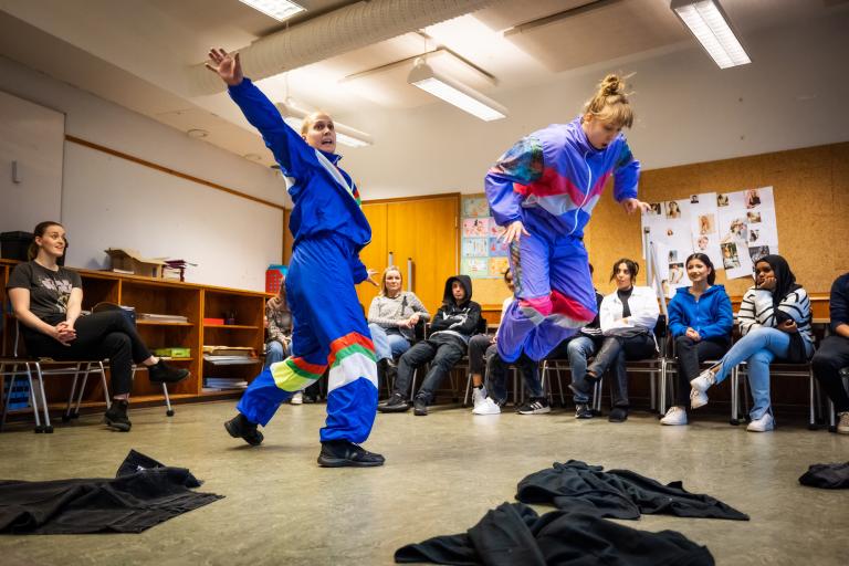 Två dansare i blå träningskläder dansar yvigt Regionteater Västs dansföreställning Sch!