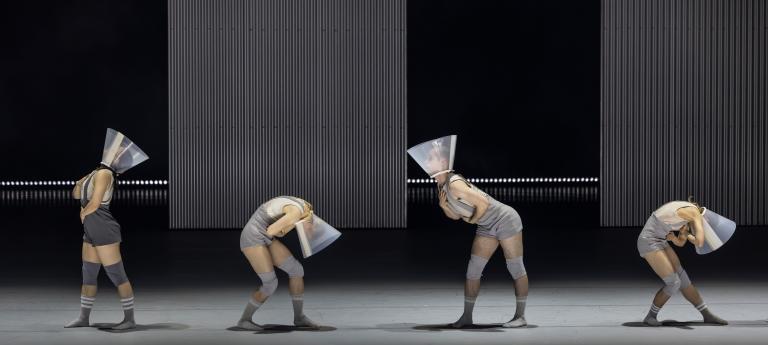 Fyra dansare i linnen och korta shorts och platsstrutar fästa runt halsen böjer sig framåt eller bakåt i Skånes Dansteaters jubileumsföreställning Wing Ding av koreorgafen Lidia Wos.