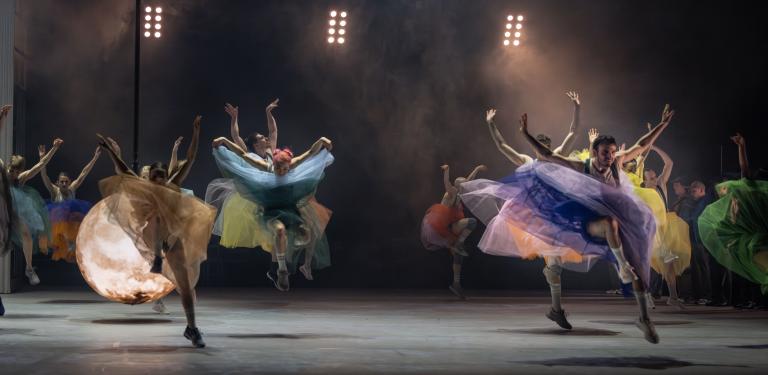 Femton dansare gör stora danssprång genom luften klädda i tyllkjola i regnbågens alla färger i Skånes Dansteaters jubileumsföreställning Wing Ding av  koreografen Lidia Wos.