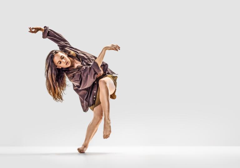 Skånes Dansteaters dansare Hanna Nussbaumer vrider överkroppen och lyfter armarna och ett ben i en vridning upp i luften.