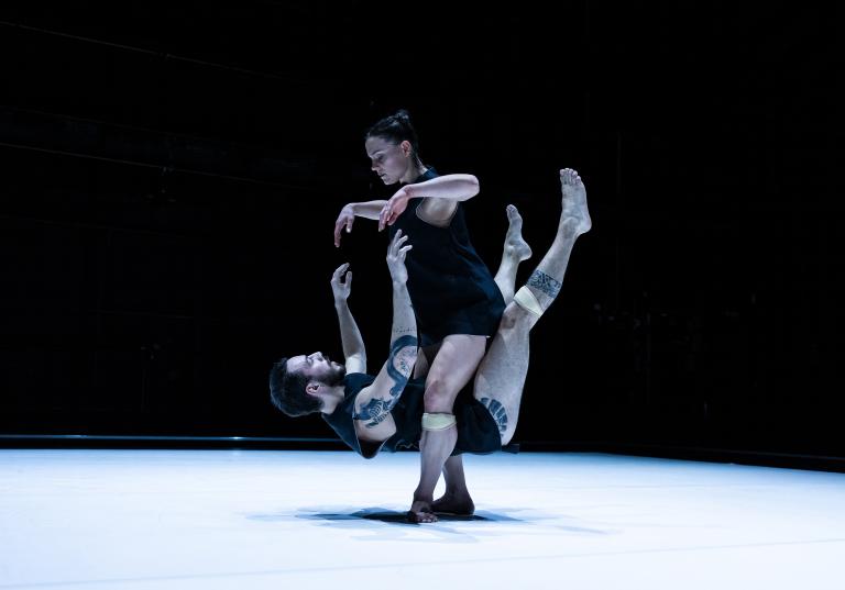 Dansaren Simone Frederick Scacchetti hålls nästan svävande runt dansaren Amy Joshs ben.