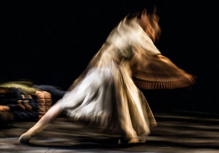 Dansaren Jing Yi Wang dansar snabbt i en cremevit klänning i dansföreställningen In Wind or Dust.